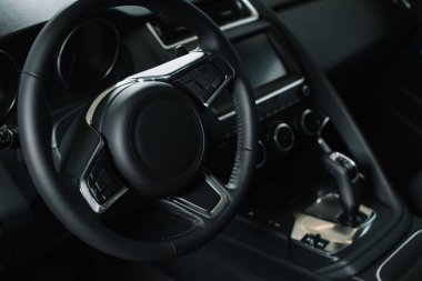 selective focus of steering wheel near gear shift handle in luxury car  clipart