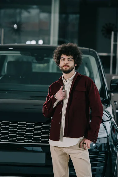 車のショールームで黒い自動車の近くに立っているハンサムな髭の男 — ストック写真
