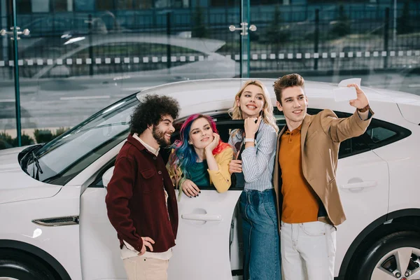 Веселая Группа Друзей Делающих Селфи Смартфоне Возле Белого Автомобиля — стоковое фото