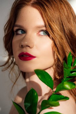 güzel genç Redhead kadın bitki ile poz ve uzağa bakıyor