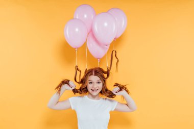 sarı üzerinde izole poz saç bağlı balonlar ile mutlu Redhead kız