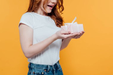 kopya alanı ile sarı üzerinde izole sürpriz Redhead kız tutan hediye kutusu kırpılmış görünümü