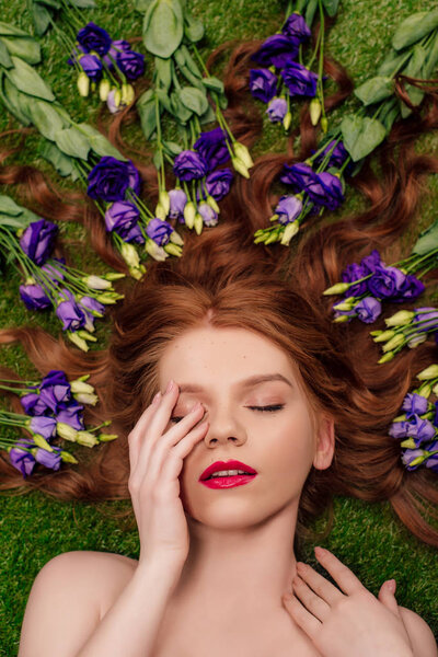 top view of beautiful young redhead woman with red lips and eustoma flowers in hair 