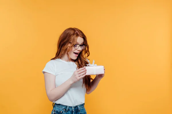 Beautiful Surprised Redhead Girl Holding Gift Box Isolated Yellow Copy — Stockfoto