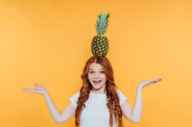 Güzel Redhead kız kamera bakıyor, gülümseyen, gebelik ve sarı üzerinde izole kafası ananas ile poz