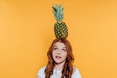 Kızıl saçlı kız sarı üzerinde izole baş ananas ile poz verirken
