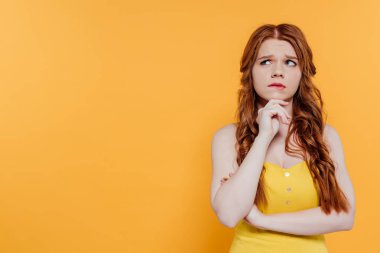 güzel dalgın Redhead kız çene yaslanır ve uzak kopya alanı ile sarı izole bakıyor