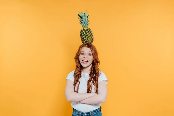 カメラを見ている赤毛の女の子 舌を貼り付け 黄色に孤立した頭の上にパイナップルとポーズ — ストック写真