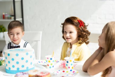 Evde Doğum günü partisi sırasında pasta ile masada oturan sevimli çocuklar