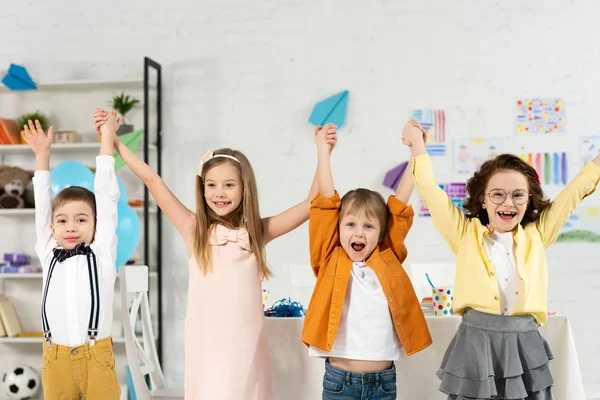 Adorables Niños Alegres Mirando Cámara Levantando Las Manos Casa — Foto de Stock