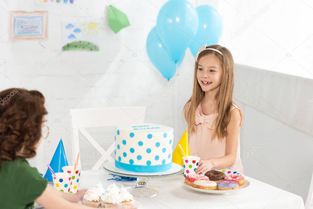 cute kids sitting at party table with cake during birthday celebration