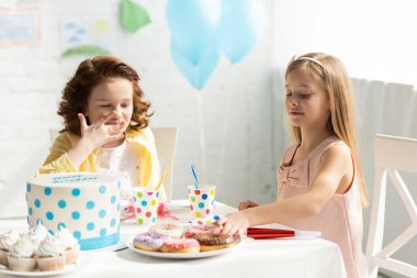 Doğum günü kutlama sırasında cupcakes ve kek ile parti masasında oturan sevimli çocuklar