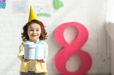 parti Cap tutan sevimli gülümseyen çocuk mevcut ve dekoratif pembe sayı yakın poz 8