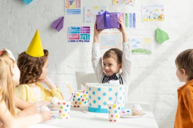 Doğum günü partisi kutlama sırasında arkadaşlarınızla masada otururken mutlu çocuk tutma mevcut