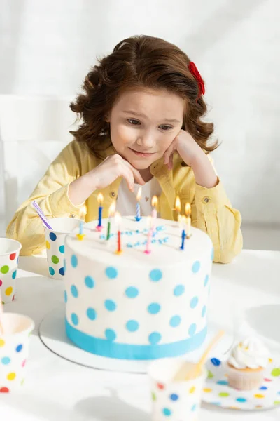 パーティーの間に誕生日ケーキを見ているテーブルで愛らしい子供の選択的焦点 — ストック写真