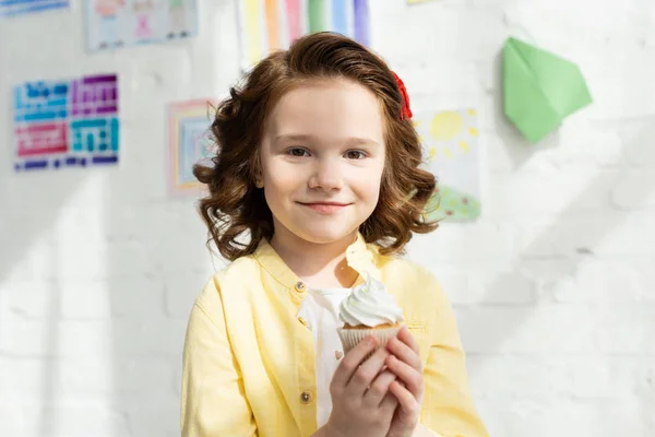 Entzückendes Kind Mit Leckerem Cupcake Und Blick Die Kamera Hause — Stockfoto