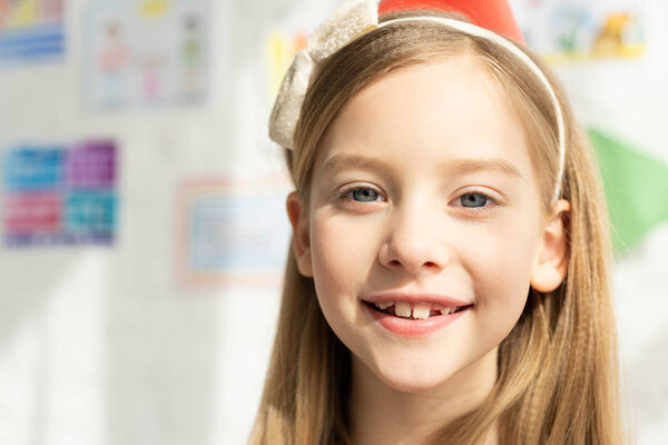 selective focus of adorable smiling kid in headband looking at camera