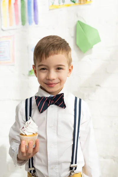 Adorable Preadolescente Chico Pajarita Celebración Delicioso Cupcake Mirando Cámara —  Fotos de Stock