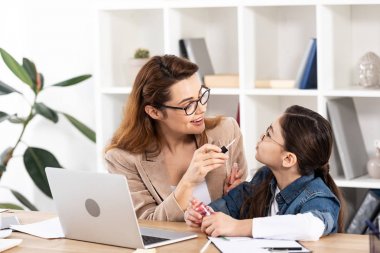 ofiste sevimli kızı dudak parlatıcı uygulayarak neşeli anne 