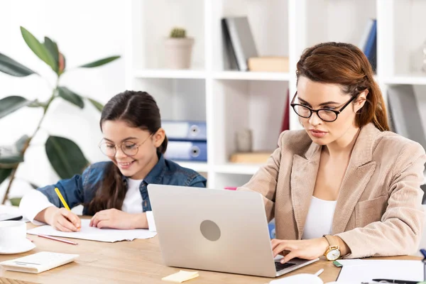 Attraktiv Mor Glasögon Med Hjälp Laptop Nära Glada Dotter — Stockfoto