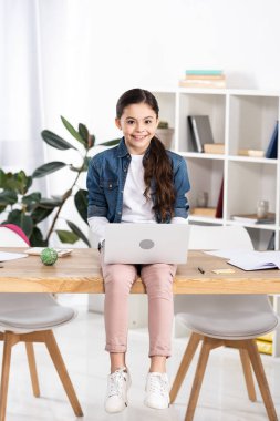 ofiste masada otururken dizüstü bilgisayar kullanan mutlu çocuk 