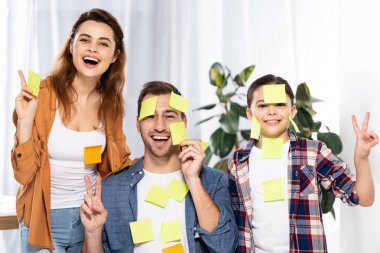 barış işaretleri gösteren yapışkan notlar neşeli ebeveynler ve sevimli çocuk 