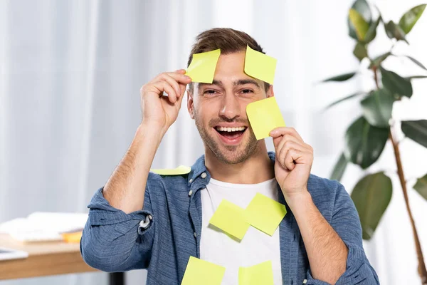 happy man in yellow and orange sticky notes looking at camera