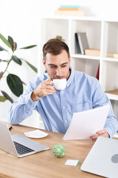 Alegre Hombre Negocios Bebiendo Café Mientras Está Sentado Oficina Sosteniendo — Foto de Stock