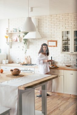 Mutfakta kahvaltı hazırlarken uzakta bakan beyaz gömlekli pretty kadın
