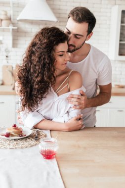 mutfakta seksi kıvırcık kız arkadaşı kucaklayan sakallı adam