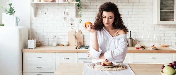 Plano Panorámico Niña Sosteniendo Naranja Mirando Panqueques Cocina — Foto de Stock