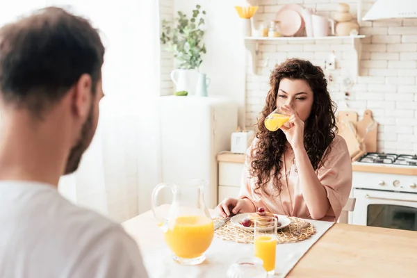 Mujer Rizada Bebiendo Jugo Naranja Mientras Está Sentada Mesa Con — Foto de Stock