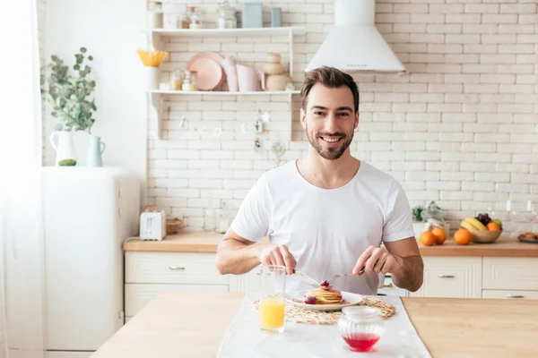 Glimlachend Bebaarde Man Wit Shirt Eten Pannenkoeken Keuken — Stockfoto