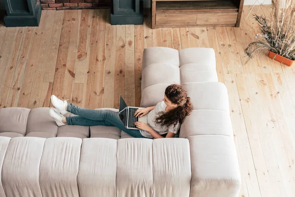 ソファに座ってラップトップを使用している女性のオーバーヘッドビュー — ストック写真
