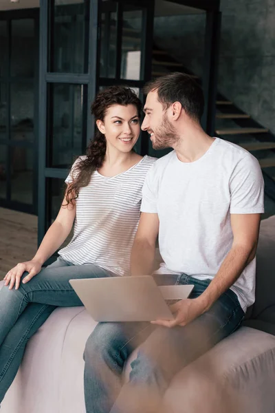 Sorrindo Casal Com Laptop Sentado Sofá Olhando Para Outro — Fotografia de Stock