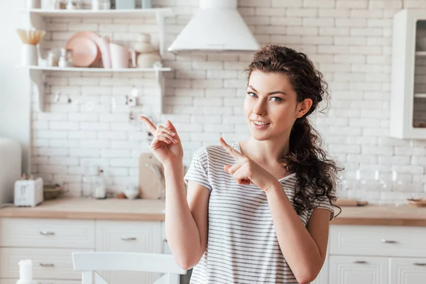 gülümseyen kıvırcık kız parmakları ile işaret ve kamera bakarak