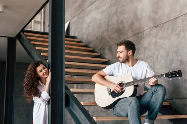 Sorrindo Barbudo Homem Sentado Escadas Tocando Guitarra Acústica Para Namorada — Fotografia de Stock