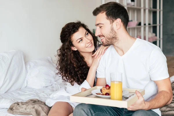ベッドで朝食を食べながらお互いを見ているカップル — ストック写真
