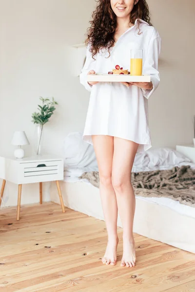 Częściowy Widok Uśmiechniętą Kobietę Koszulce Trzyma Tacę Śniadaniem Sypialni — Zdjęcie stockowe