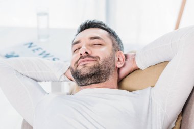gözleri kapalı yakışıklı sakallı adam seçici odak ve Eller Arka evde kanepede istirahat