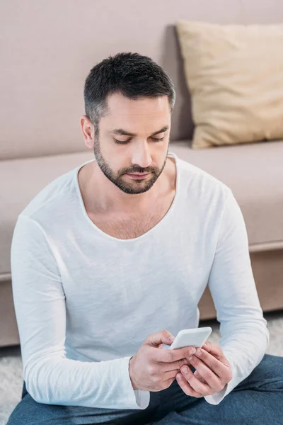 Fokuserad Stilig Man Casual Kläder Sitter Och Använder Smartphone Hemma — Stockfoto