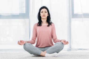 Gözleri Lotus 'ta kapalı güzel bir kadın. Evde oturma odasında meditasyon yapıyor. 