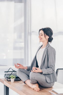ofiste Lotus Pose masada meditasyon takım elbise güzel gülümseyen iş kadını
