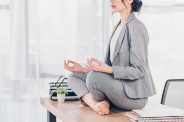 ofiste Lotus Pose'de oturmave meditasyon takım elbiseli iş kadınının kırpılmış görünümü