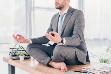ofis masasında Lotus Pose meditasyon işadamı kırpılmış görünümü