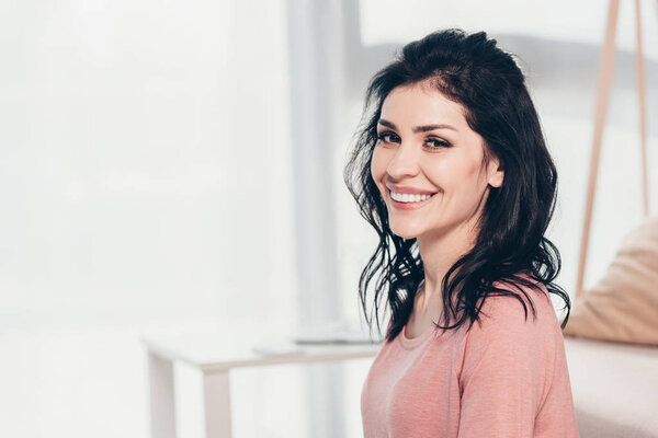 beautiful smiling woman in casual clothes looking at camera and smiling at home with copy space