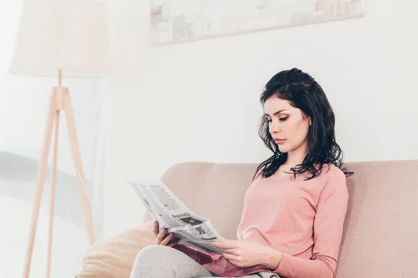 Hermosa Mujer Seria Sentada Sofá Leyendo Periódico Casa — Foto de Stock