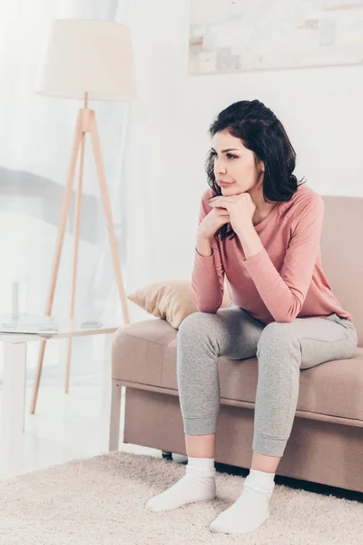 Verwirrte Frau Sitzt Auf Couch Und Stützt Kinn Mit Händen — Stockfoto