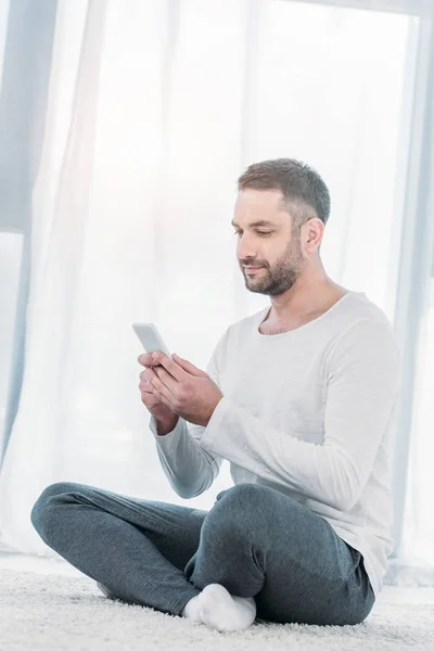 Handsome Man Casual Clothes Sitting Carpet Using Smartphone Home Sunlight — Stock Photo, Image