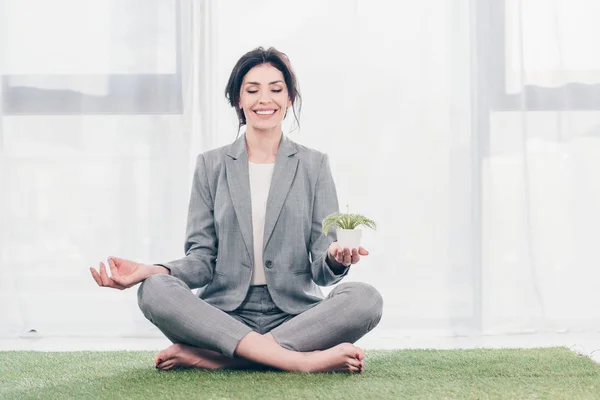 Piękne Bizneswoman Siedzi Trawie Mata Lotus Pose Medytowanie Trzymanie Doniczki — Zdjęcie stockowe